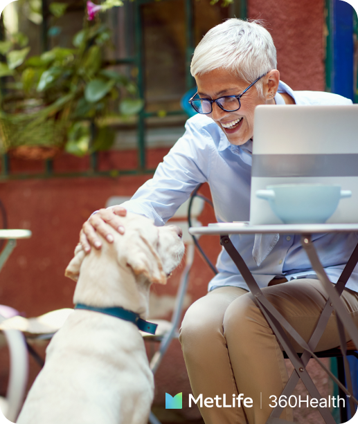 Lady sitting outside at a cafe on her laptop, patting a dog