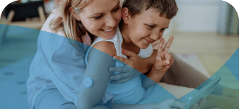 Mother and son, wearing a diabetic device on his arm, looking at a phone