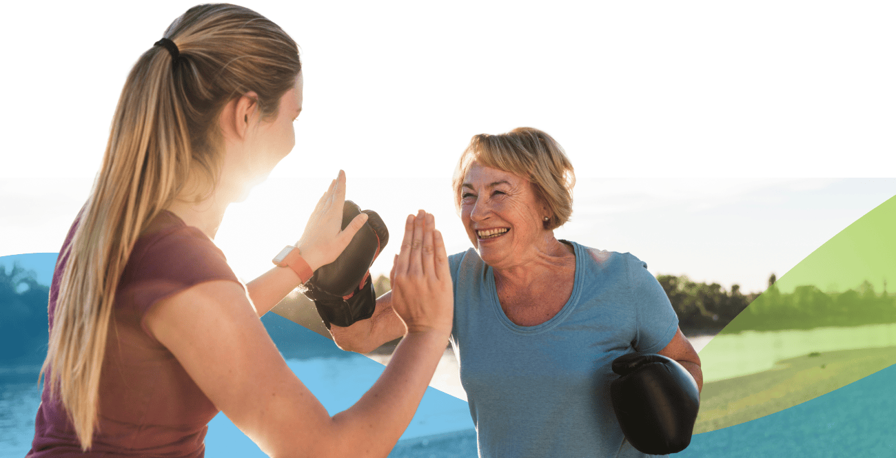 Older woman boxing with a young lady outside