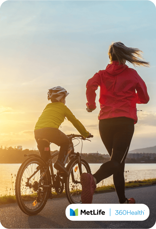Woman running alongside her son, riding a bike