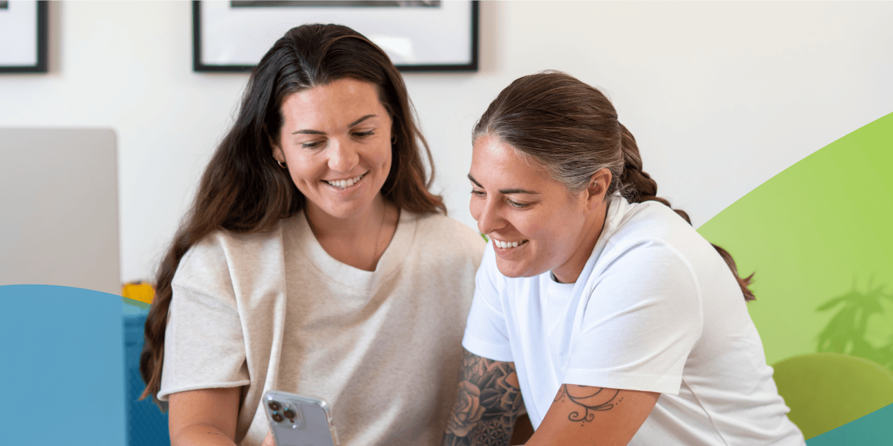 Two women at home looking at a phone together. 