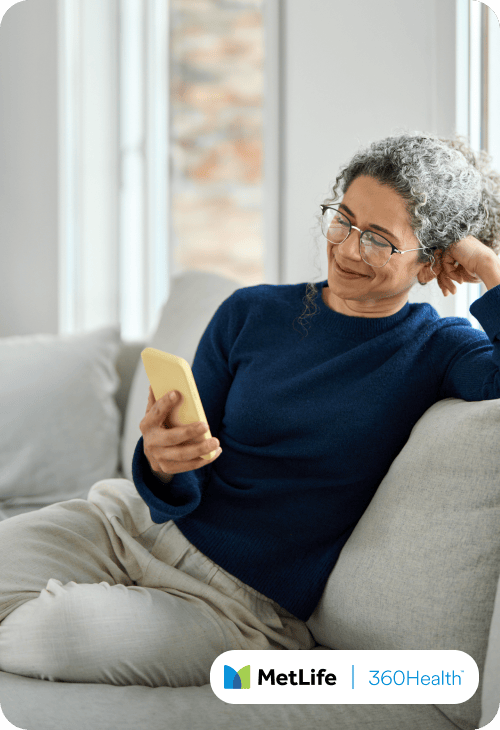 Middle aged woman on her couch smiling at her phone