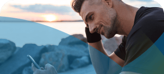 Man looking at his phone outdoors while the sun sets.