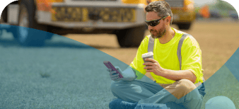 Man in high-vis sitting down outside on his phone