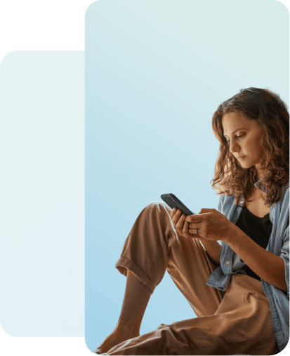 Woman sitting on the ground on her phone.