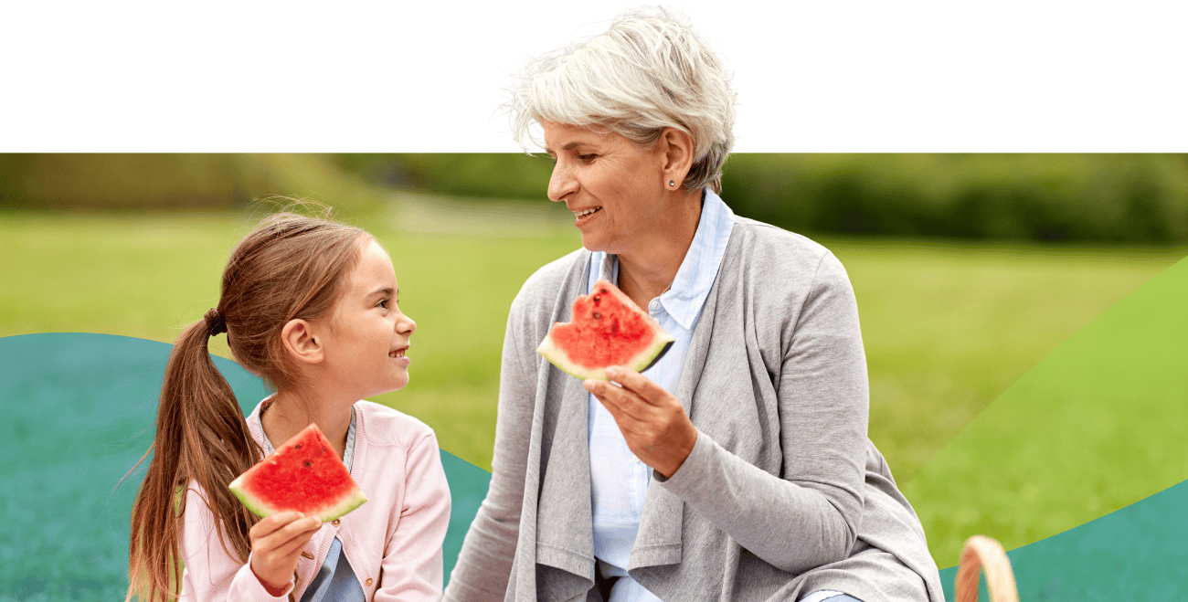 Older woman and young girl eating watermelon outside