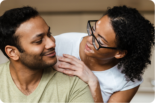 Woman smiling at man over his shoulder comfortingly.