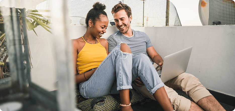 A couple sitting on the floor smiling.